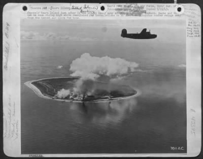 Thumbnail for General > Theater #23.  An Army Liberator Views Damaged [Japanese Held] Nauru.  Smoke From Two Fires Can Be Seen.  Also, Smoke And Dust From Three Hits Near The Phosphate Plants And The Barracks Area Are Seen To The Left Of The Column Of Black Smoke.