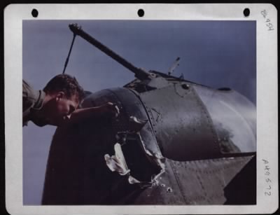 Battle Damage > Msgt Robert Henman Of Madison, Wisconsin Examines Battle Damage To The Tail Of A Consolidated B-24 In England.