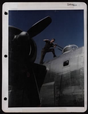 ␀ > Pfc. Loyd D. Taylor Of Cranby, Missouri, Cleans Twin .50 Cal. Machine Guns On Top Turret Of A Consolidated B-24 At A Base In England.