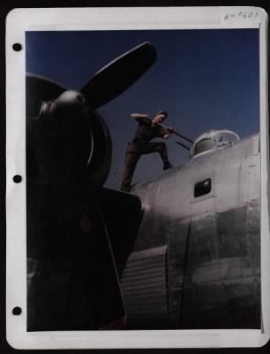 ␀ > Pfc. Loyd D. Taylor Of Cranby, Missouri, Cleans Twin .50 Cal. Machine Guns On Top Turret Of A Consolidated B-24 At A Base In England.