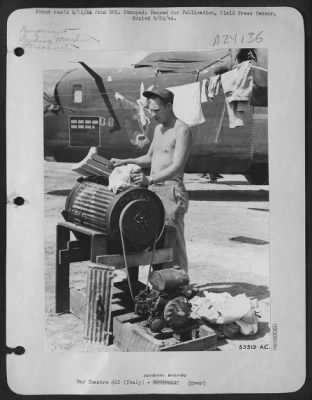 Thumbnail for Consolidated > Sgt. John H. Dowell, 1255 Page St., Bristol, Va., is a propeller specialist with a Consolidated B-24 Liberator Bomb Group in the 15th Air Force, Italy. In his spare time he invented this washing machine. This picture shows the Sgt. At work with the