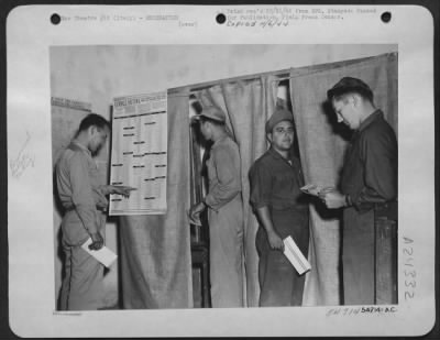 Thumbnail for Consolidated > Election day rolls around and these members of a 15th Air Force B-17 Flying Fortress Group in Italy go to the polls to cast their votes for the candidates in the Federal Election. Sgt. Charles Leonard (left) reads the New Jersey list of candidates in