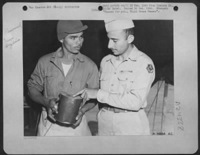 Consolidated > Left, Pfc. Maximiano Pedro de Silva, cook of the First Brazilian Fighter Squadron serving in Italy having a can of GI food identified by the official identifier in the Brazilian mess, Cpl. Joseph A. Rodeiro, from Tampa, Florida.