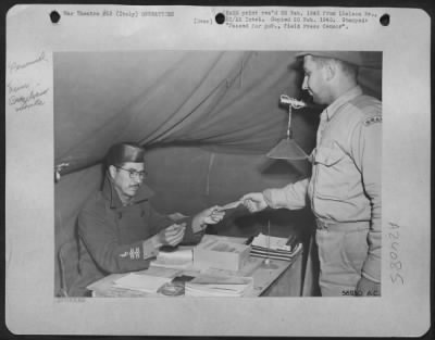 Thumbnail for Consolidated > Left, Maj. Ovidio Beraldo, From Sao Paulo, Finance Officer Of The First Brazilian Fighter Squadron, Pays Off Pvt. Augusto Villas-Boas, An Orderly Room Clerk.  The Maj. Was Once An Assistant To The Minister Of The War.  The Pvt. Was A Lawyer In Civilian Li