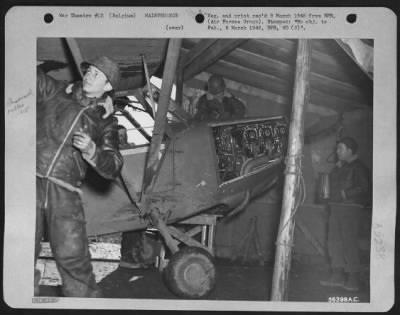 Thumbnail for Engines > This is the only hangar for the Liaison Squadron's planes. Just a windbreak for the mechanics, it is made of scrap lumber and a German tent floor. Left to right are: Cpl. Henry Brief, 351 Riverdale Ave., Brooklyn, N.Y.; Sgt. Kirby L. Jensen, Albany