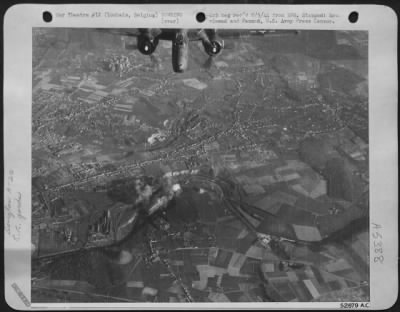 Thumbnail for Loubais[Sic] > Black and white smoke rises from direct hits (center) on the railroad marshalling yards at Loubais, Belgium, as a Douglas A-20 Havoc light bomber of the 9th AF, roars over the target.