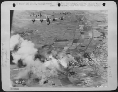 Hatvan > Consolidated B-24 Liberator bombers of the 15th Air force leave the smoldering target; railroad sidings and repair facilities in Hatvan, Hungary on Sept 20, 1944. The target was seen to be well covered with bomb bursts.