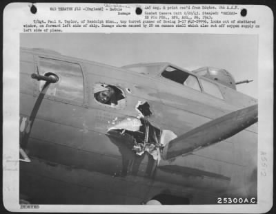 Thumbnail for Battle Damage > T/Sgt. Paul R. Taylor, of Randolph Minn., top turret gunner of Boeing B-17 #42-29996, looks out of shattered window, on forward left side of ship. Damage shown caused by 20 mm cannon shell which also cut off oxygen supply on left side of plane.