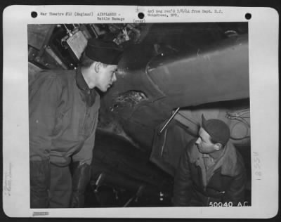 Thumbnail for Battle Damage > England-2nd Lt. Paul Keller, 4015 Brownsville Road, Pittsburg, Pa., inspects a 20 mm bullet hole on the leading edge of the left wing root of his Thunderbolt P-47 fighter plane. Pictured with his is his crew chief, S/Sgt. Jack E. Morley, 1408 East