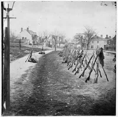 3904 - Petersburg, Va. Row of stacked Federal rifles; houses beyond