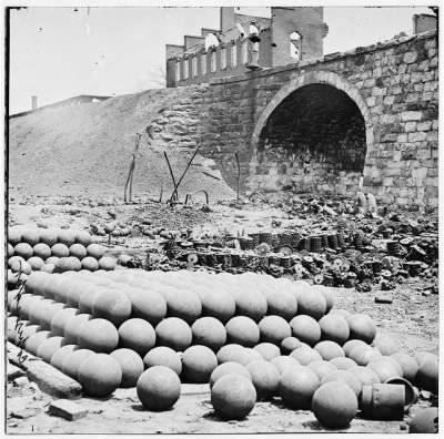 Thumbnail for 4157 - Richmond, Va. Piles of solid shot, canister, etc., in the Arsenal grounds; Richmond & Petersburg Railroad bridge at right