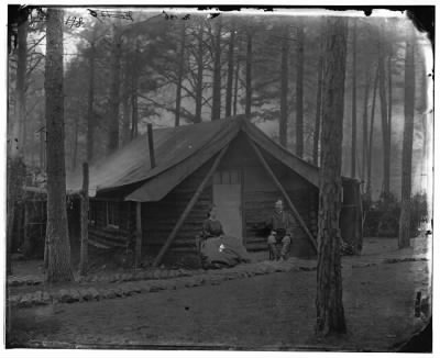 Thumbnail for 677 - Brandy Station, Va. Col. John R. Coxe, A.C.S., and lady seated before his log-cabin winter quarters at Army of the Potomac headquarters