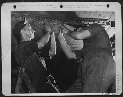 Thumbnail for General > Cpl. Harold W. Kitzman, Pittston, Pa., and Cpl. William A. Hester, Steele, Mo., ground crew members, are shown tightening long line of bolts which hold wing panel of ofrtress in place. Flak had seriously damaged outer wing panel, but within a few