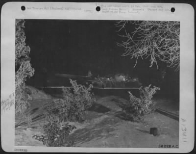 General > Winter tracery frames a U.S. 8th AF Boeing B-17 Flying ofrtress being repaired by ground crewmen preparing it for a dawn take-off to bomb targets deep in the heart of Germany. ENGLAND.