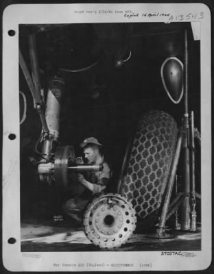 Thumbnail for Tires & Wheels > The Huge B-17 Undergoing Modification For Combat, At An 8Th Air Force Base Depot, In England, Is Jacked Up.  Pvt. Jack Michaelson, Fairbanks, Ill., Cleans Old Grease From The Axle, Before Remounting Wheel.