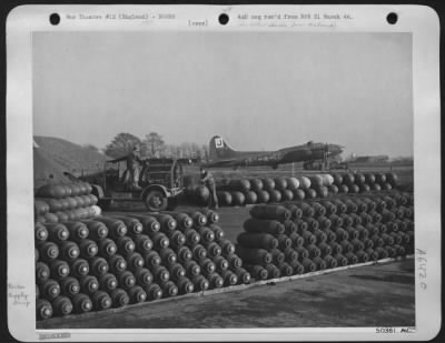 Thumbnail for General > Reserve stores of a large variety of high explosive bombs are stacked up at an operational station in preparation for future missions. Ordnance men are seen swinging a blockbuster into place with aid of crane.