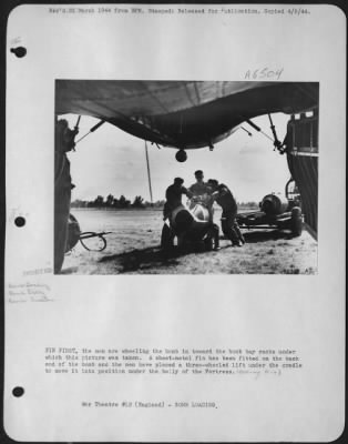 Thumbnail for General > FIN FIRST, the men are wheeling the bomb in toward the bomb bay racks under which this picture was taken. A sheet-metal fin has been fitted on the back end of the bomb and the men have placed a three-wheeled lift under the cradle to move it into