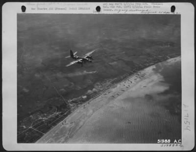 General > One of the many B-26 Martin Marauders of the Ninth Air force is shown over the coast of France during the early morning giving a cover to the landing craft shown on the sandy beaches below. These hard hitting medium bombers with their fighter escort