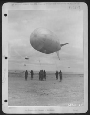 Thumbnail for General > for protection against enemy strafing on the French coast, these men of the Anti-aircraft balloon squadron are shown in the process of hoisting up another to join those already in service.