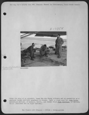 Thumbnail for Installations > Under the wing of an aircraft, these 9th Air Force officers set up operations at a captured German airfield somewhere in France. Left to right are: Lt. John Veria, Operations Officer, of Antioch, Calif., and Glider Pilot Jack Phillips, of Oakland