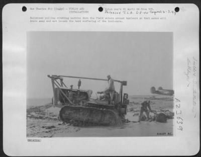 Thumbnail for Consolidated > Bulldozer pulling ditching machine thru the field waters around taxiways so that water will drain away and not loosen the hard surfacing of the taxi-ways.