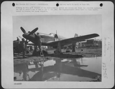 Thumbnail for Consolidated > Working on this A-36 Invader of the Mediterranean Allied Air Forces are these two aviation mechanics who had to cross a sea of mud to get to the plane. The fighter-bomber shown here has been instrumental in downing two enemy aircraft.