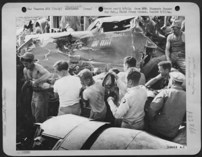 Thumbnail for Consolidated > A wounded gunner is shown being carried away from his wrecked B-24 Liberator bomber of the 15th AF which was hit by flak over an enemy installation in southern France. Photo was taken just after the plane made a crash landing at its base in southern