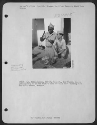 Consolidated > ITALY-Sgt. Willie Landry, 2108 St. Louis St., New Orleans, La., is getting ready to put the knife to some delicious beef. Looking on is the Unit's mascot, Pasquale.