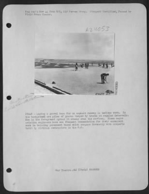 Consolidated > ITALY-Laying a gravel base for an asphalt runway is tedious work. In the background are piles of gravel dumped by trucks at regular intervals. Men in the foreground spread it evenly over the surface. These negro aviation engineers have won frequent