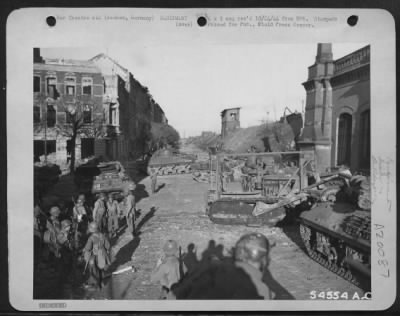 Thumbnail for Consolidated > While 9th AF fighter-bombers dive-bomb the city of Aachen, Germany, American tanks and tank-destroyers await the termination of the air assault before entering the town. The railroad embankment at upper right, on the outskirts of Aachen, separates