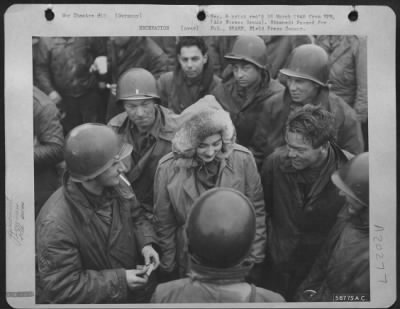 Consolidated > Aviation engineers of the IX Engineer Command, constructing an airstrip in Germany for 9th Air Force fighter-bombers, gather around Dorothy Myrick, Whiting, Indiana, a visiting Red Cross worker. The engineers have built air bases in France, Belgium