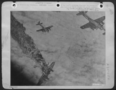 Consolidated > Flame, smoke and debris stream from a B-17 Flying Fortress plummeting earthward as other U.S. Army 8th Air Force planes loose their bombs on a synthetic oil plant at Merseburg, Germany. Enemy fire over Germany hit the fort directly, tearing off the