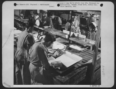 Thumbnail for Consolidated > In this section of one laboratory-only one of the many used by aerial reconnaissance section-several teams of men are at work making some of the prints that result from one photo-reconnaissance mission. The teamwork here pays off in increased