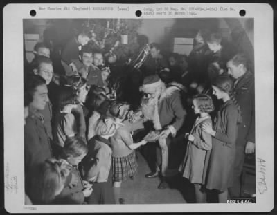 Thumbnail for Consolidated > 'Christmas Daddies'.  S/Sgt. Anthony Osso, Hamilton, Ohio, Playing Santa Claus, Passes Out Presents To Orphans And The Sons And Daughters Of British Soldiers At A Christmas Party Given By The Soldiers Of The Tactical Depot Of The 9Th Air Service Command.