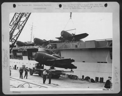 Thumbnail for Consolidated > Re-Deployment -- Fighter Planes - At The Liverpool Docks, Huge 60 Ton Cranes Gently Lift A 6 3/4 Ton Republic P-47 Thunderbolt To The Flight Deck Of A Grain Ship Converted Into A Pocket Aircraft Carrier.  These Are The Ships Which Doubled As Baby Flat-Top