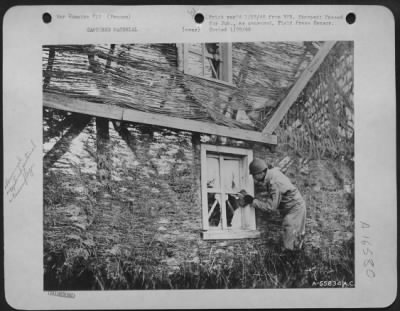 Thumbnail for General > Cpl. Marion R. Sams of High Point, N.C., eavesdrops through the paper window of one of the house's constructed by the Nazi for the purpose of camouflaging some small workshops in France.