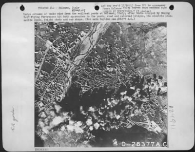 Consolidated > Large columns of smoke rise from the railroad yards at Bolzano, Italy, after bombs dropped by Boeing B-17 Flying Fortresses hit both approaches to the yards, road and railroad bridges, the electric locomotive sheds, freight sheds and car shops.