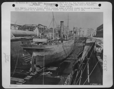 Thumbnail for Consolidated > Large drydock, containing damaged 280-foot merchant vessel & 150-foot coaster was flooded by Germans, repaired & pumped dry by Americans. Another drydock is behind curved wall at left.