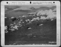 Flying High above the scattering clouds, and leaving unmolested a small village in the center foreground this lone Consolidated B-24 Liberator, one of a formation, is on its way to bomb the Nazi submarine docks at Bremen. 392nd Bomb Group. - Page 1