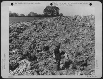 Thumbnail for Intruder Damage > A Near Miss Was This Bomb Dropped By An Enemy Night Raider Somewhere In England.  This Crater And One Adjacent To It Made By A Bomb Which Dug Deeply Into The Soft Soil Near A Taxiway At An Airdrome.  The Officer Standing At The Bottom Of The Pit Is Reachi