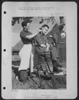 Thumbnail for General > All the conveniences of a modern barber shop at home are present in this open-air trimming outfit rigged up by two 9th AF mechanics stationed at an airfield in France. Cpl Glen E. Grunseth of Route 3, Barron, Wisc., the barber wrapped up in the white