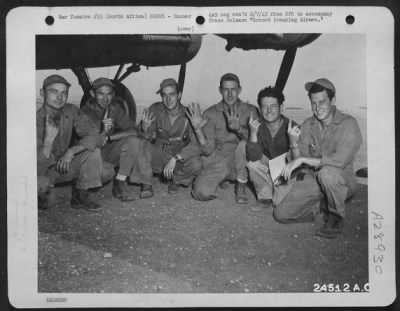 Consolidated > Record Breaking Airmen-These American Airmen in North Africa are indicating their own versions of the Victory symbol: the number of Axis planes each has shot down. All are gunners of a record-breaking Flying Fortress crew which has accounted for 17