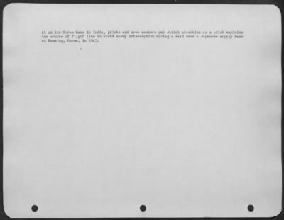 Consolidated > At An Air Base In India, Pilots And Crew Members Pay Strict Attention As A Pilot Explains The Choice Of Flight Line To Avoid Enemy Interception During A Raid Over A Japanese Supply Base At Kamaing, Burma, In 1943.