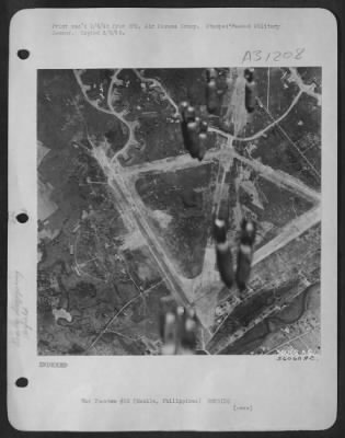 Consolidated > The start of another 13th Air Force raid on Nichols Field, Manila, was photographed by combat cameramen who made their pictures as the bombs began the screaming journey to the target. Earlier13th Air Force attacks caused the damage to runways, shops