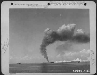 Thumbnail for Consolidated > As a result of enemy bombs, a cargo ship burns on the horizon near Tacloban, Leyte. An LST is laying a protective smoke screen to protect other LSTs and ships in the harbor. Philippine Islands.