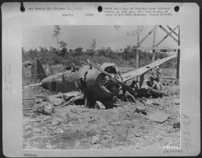 Thumbnail for Consolidated > In the shadow of a Jap fighter's wing, construction workers erecting a new control tower stop for a swig of water and a few minutes of rest. Palawan Island, P.I.