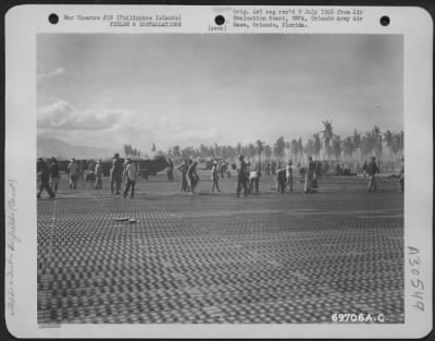 Thumbnail for Consolidated > Hundreds of Filipinos help American soldiers bolt the steel mat into place during construction of a landing strip in the Philippine Islands.