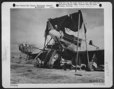 Thumbnail for Consolidated > Under the makeshift canopy set up to protect him from the blazing sun, a mechanic works on one of the North American P-51 "Mustangs" of the 5th Air Force Fighter Command at an advanced Phililppine Airbase. With bombs and machine guns, these fighters