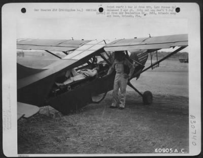 Thumbnail for Consolidated > An enlisted pilot takes a final check on his passenger's comfort before he takes off for a rear area hospital in his Stinson L-5. Philippine Islands.