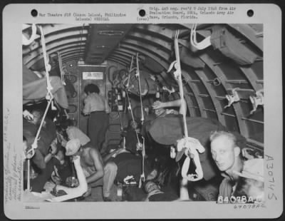 Consolidated > Wounded troops enroute from Rosalie Airstrip to Neilson Field, being evacuated from the 409th Medical Collecting Company. Medical Technician and nurses are shown giving aid and treatment in flight. Litters are arranged three deep on both sides of the